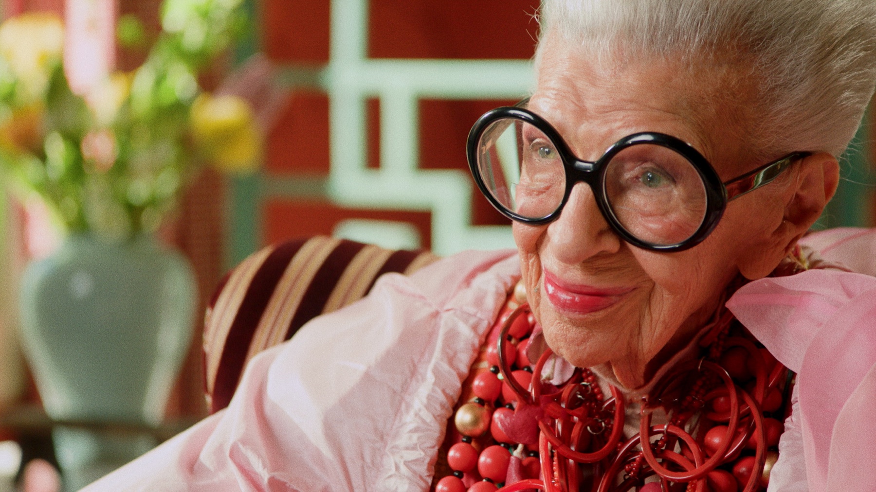 Iris Apfel seated in a richly colored interior